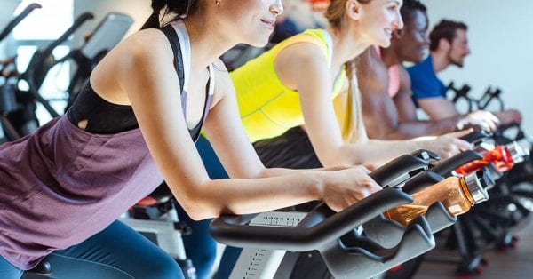 Very fit Asian woman and her friends on fitness bike in gym; blog: 9 Exercises for Joint Health