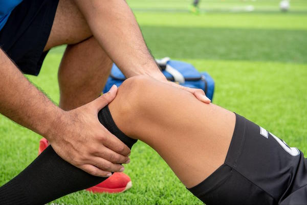 an athletic trainer working with a soccer player as one of the ways to Protect Your Knees During Sports